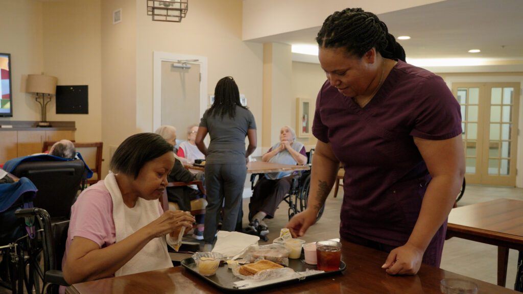 A nurse assists a woman dining at a respite care facility