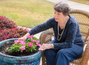 a woman smiles and gardens at a skilled nursing facility