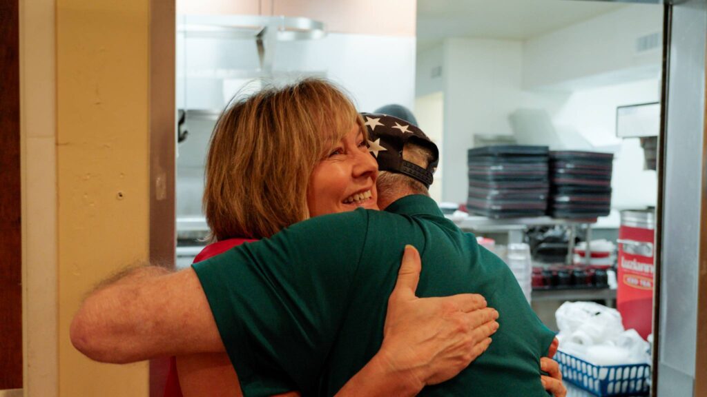 a woman hugs a resident at a skilled nursing facility