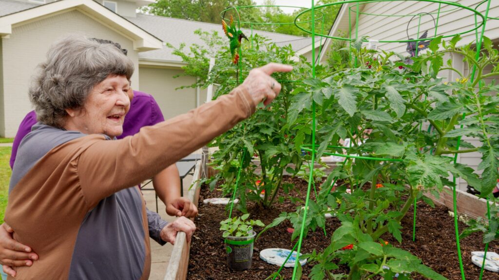 A woman points to a garden at a long term care facility